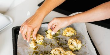 Hands of Persons Holding Baked Cauliflower