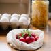 Organic fresh radishes in reusable bag placed on kitchen table near box with eggs